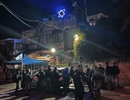 Israeli occupation forces stand in front of the Ghawi family home in Sheikh Jarrah that was taken over by Israeli settlers in 2009 and placed a neon Star of David on top of it. Photo taken in May 2021. (Photo: Mohammed El-Kurd)