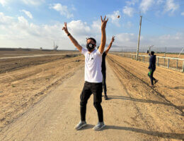 Palestinians after crossing the border fence with Israel from Khan Yunis in the southern Gaza Strip on October 7, 2023. A Palestinian with a mask raises the "V" sign as he crosses the border fence.