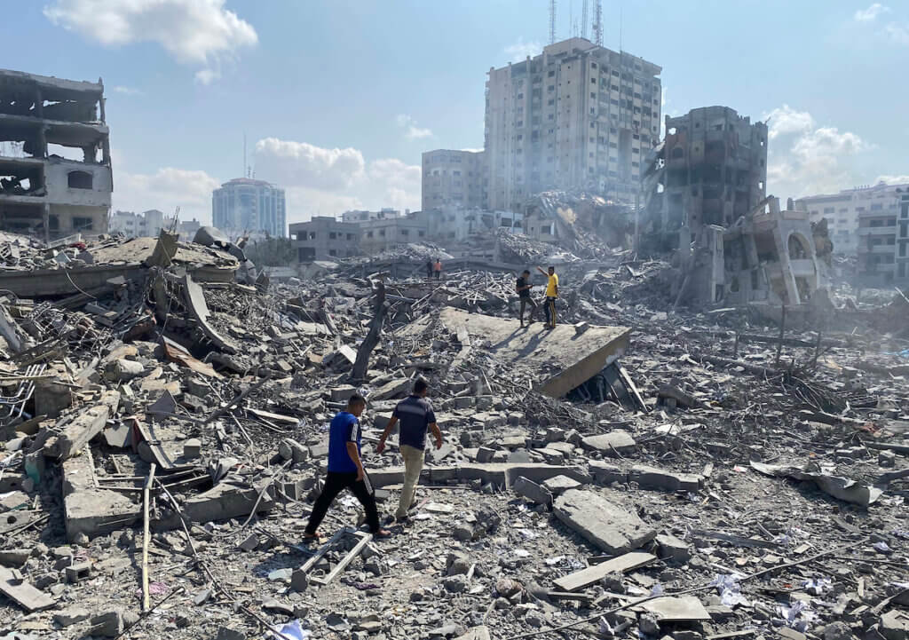 Two men walk amid the rubble in the al-Rimal area of Gaza following an Israeli airstrike on the neighborhood on October 9, 2023.