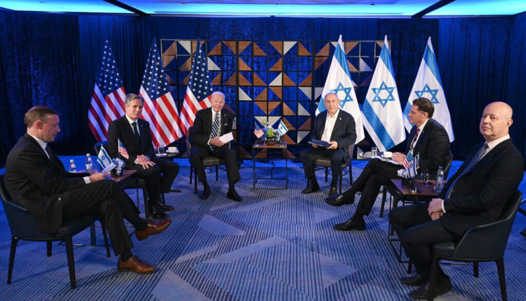 U.S. President Joe Biden visits Israel and meets Israeli Prime Minister Benjamin Netanyahu in Tel Aviv, October 18, 2023. Netanyahu and Biden are seated with the Israeli and American flags behind them, respectively, while each is flanked by their aides and government officials, including U.S. Secretary Antony Blinken.