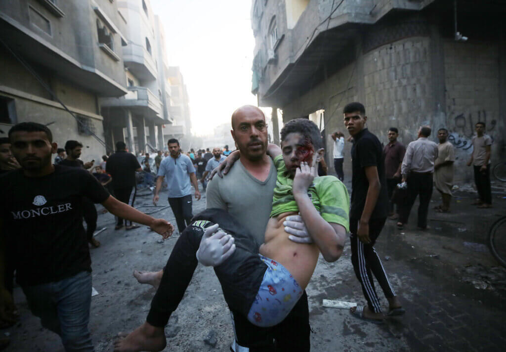 A man holds a wounded boy in his arm as they evacuate the site of an Israeli airstrike in Deir al-Balah, in the southern Gaza Strip, October 18, 2023.