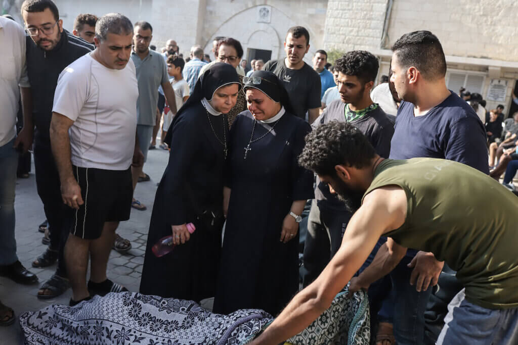 Two Palestinian nuns look down on the dead body of one of the victims of the Israeli bombing of the Greek Orthodox Church in Gaza, October 20, 2023.