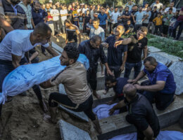 A Palestinian man lowers a white-shrouded body into a grave in the southern Gaza Strip city of Rafah, after several members of the al-Hijazi family were killed in an Israeli airstrike.