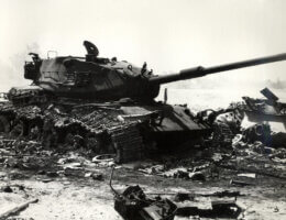A black-and-white photo shows the ruins of a knocked-out Israeli M60 tank amongst the debris of other armor after an Israeli counterattack in the Sinai during the 1973 October War.