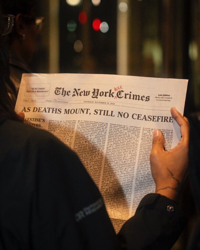 A protester holding a mock newspaper printed in the style of the New York Times with the headline 'As Death Mount, Still no Ceasefire.' (Photo: Hany Osman)