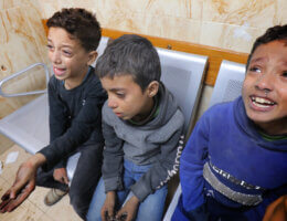 Three Palestinian boys sit on chairs in a hospital, distraught and crying, following an airstrike in the central Gaza Strip town of Deir al-Balah. (APA Images)