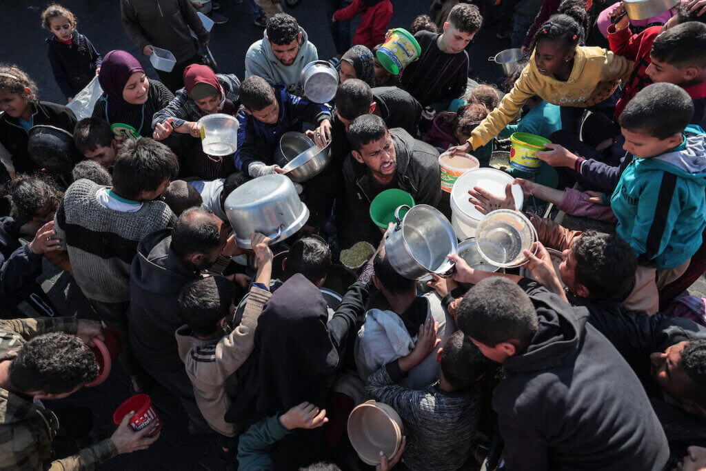 Palestinians gather with pots to receive food at a donation point provided by a charitable organization in Rafah in the southern Gaza Strip, on December 19, 2023. (Photo: Bashar Taleb/APA Images)
