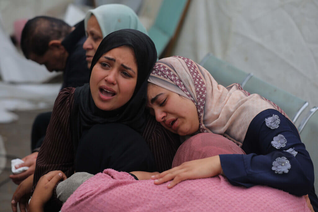 Two Palestinian women embrace as they cry and mourn the loss of loved ones killed by Israel in the al-Maghazi refugee camp in the central Gaza Strip