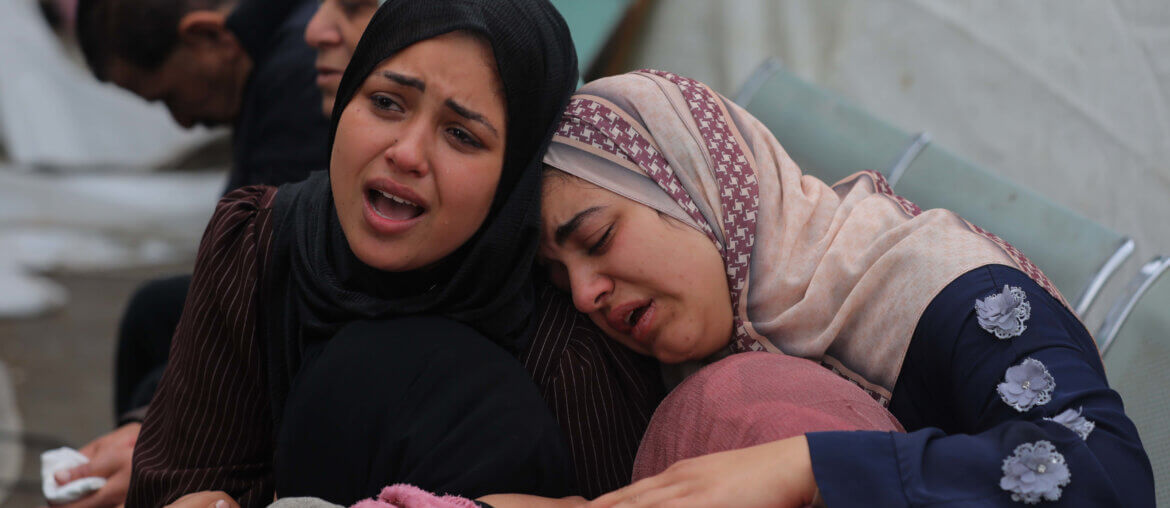 Two Palestinian women embrace as they cry and mourn the loss of loved ones killed by Israel in the al-Maghazi refugee camp in the central Gaza Strip