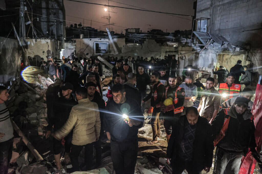 People struggle to recover bodies and survivors from under the rubble of a building hit by an Israeli airstrike on Rafah in the southern Gaza Strip, December 28, 2023. (Photo: by Bashar Taleb/APA Images)