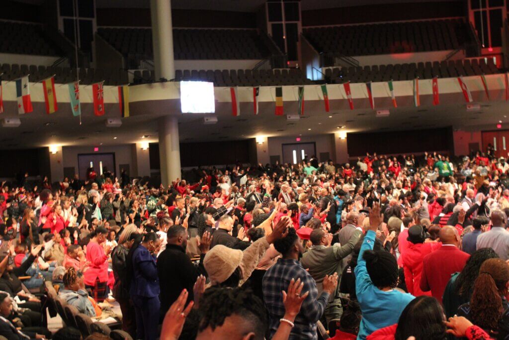 Congregants at New Birth raise their hands in prayer at the Christmas Eve service. (Photo: Sophia Qureshi/285 South)