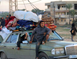 A Palestinian man sits on a car transporting blankets, mattresses, and other belongings of displaced Palestinians in the Gaza Strip.