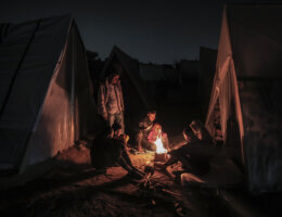 Displaced Palestinians huddle around a fire to keep warm in a makeshift camp in Rafah, southern Gaza, near the border with Egypt, December 31, 2023. (Photo: Bashar Taleb/APA Images)
