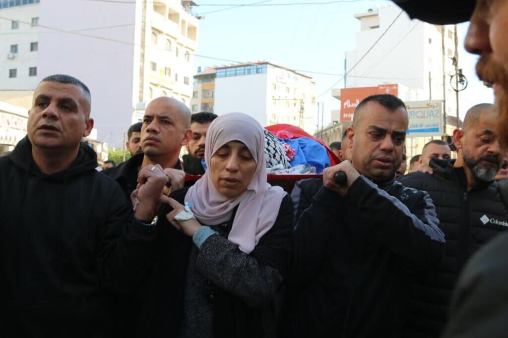 A Palestinian mother carries the body of her son on her shoulders during a funeral in Tulkarem in the occupied West Bank