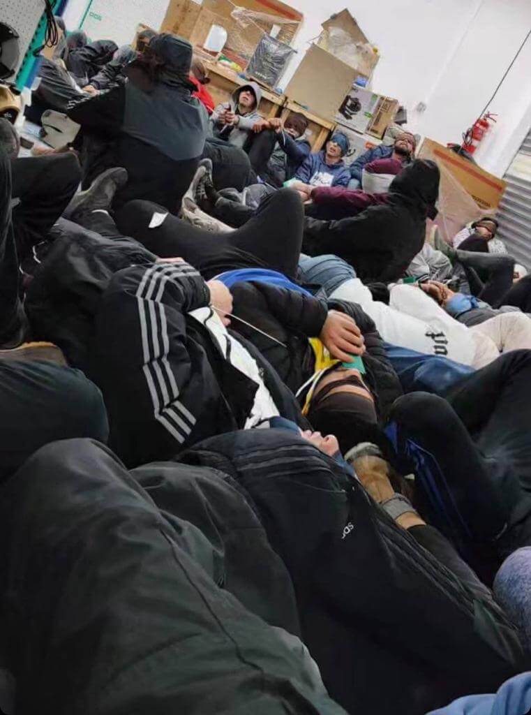 A crowded room of Palestinians, their hands tied and their eyes blindfolded, sit and lie down in a room after being detained by Israeli forces in the Tulkarem refugee camp