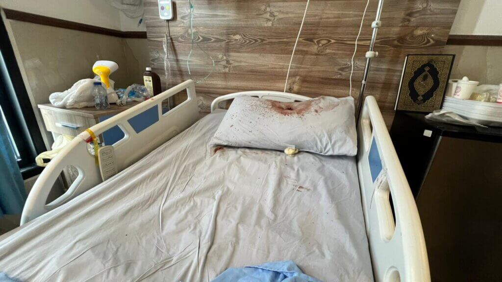 The pillow of the hospital bed where Israeli forces assassinated Basel al-Ghazawi is stained with blood. A bullet hole can be seen going through the center of the pillow