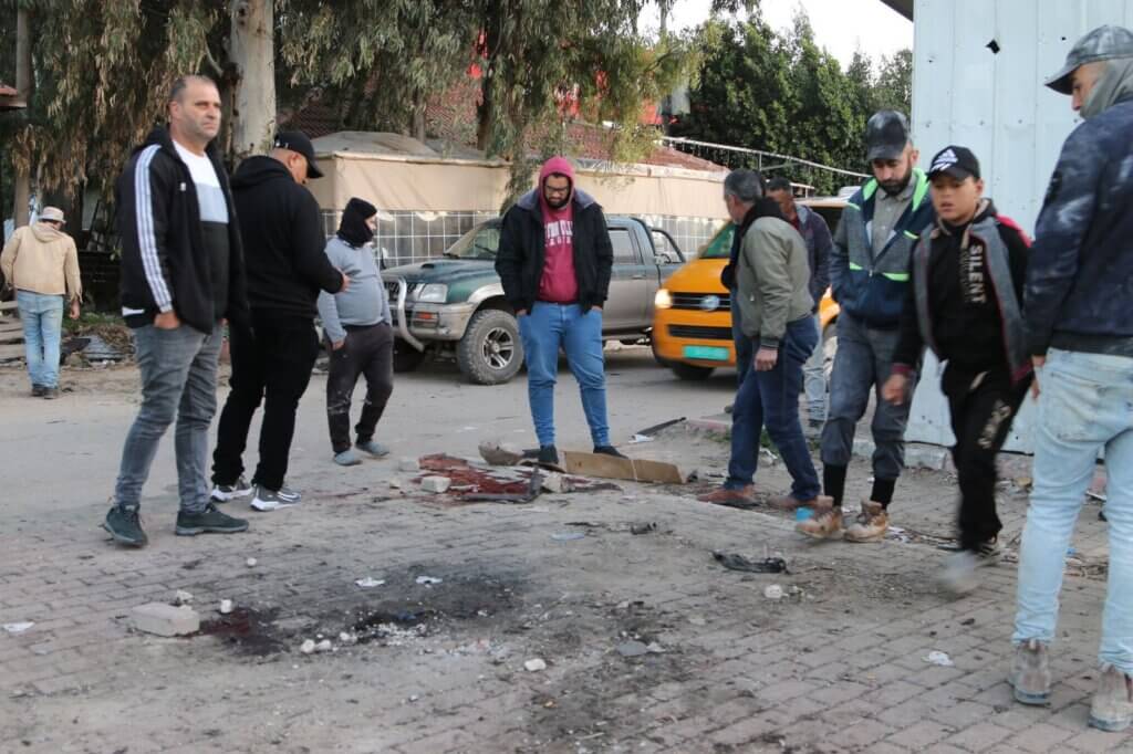 A group of Palestinians stand around the site of an Israeli airstrike that killed 7 Palestinians in Jenin in the occupied West Bank