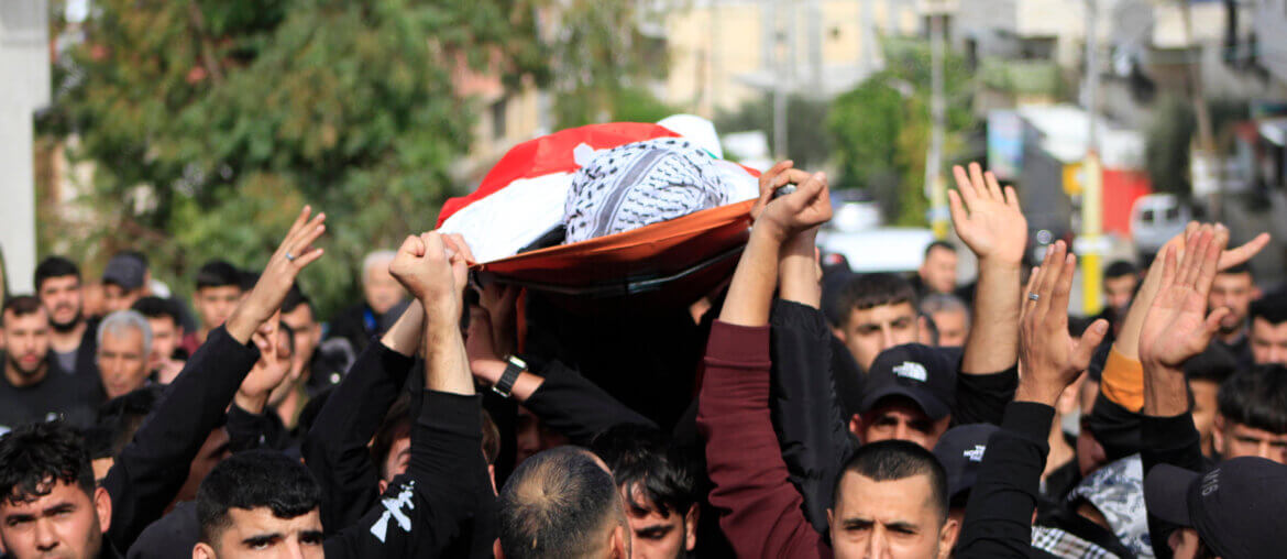 Mourners carry the flag-draped body of 17-year-old Mahmud Bassem Abu Haniyeh, killed in an Israeli raid on the occupied West Bank town of Azzun, during his funeral on December 10, 2023. (Photo: Mohammed Nasser / APA Images)