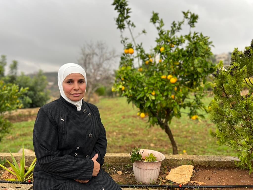 Aman Nafi', wife of Nael Barghouti, beside the citrus tree planted by her imprisoned husband, outside her home in the village of Kobar near Ramallah. (Photo: Zena al-Tahhan)