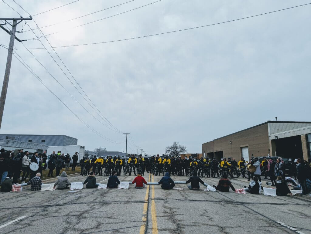 Protesters blocking the Woodward MPC manufacturing facility in Niles, Illinois with riot police in the background, waiting to arrest activists, February 7, 2024. (Photo: Instagram/@jeegheel)