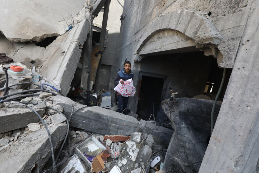 A Palestinian boy searches and sifts through the rubble of a home destroyed in an Israeli airstrike.