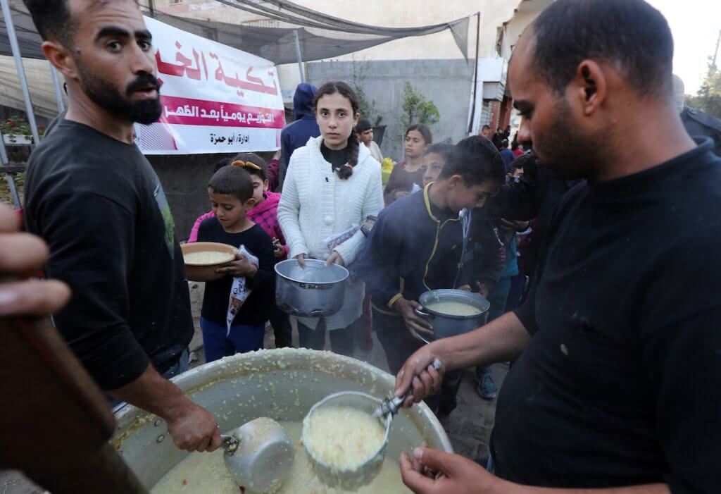 Displaced Palestinians receive food donated by a charity before an iftar meal on the third day of Ramadan in Deir al-Balah in the central Gaza Strip on March 13, 2024. (Photo: Omar Ashtawy/APA Images)