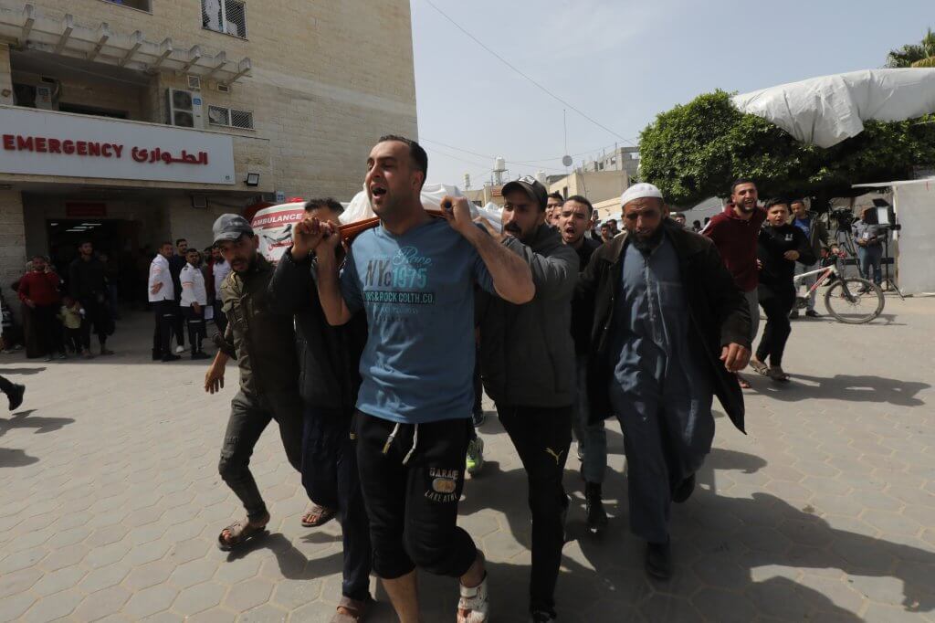 Relatives of Palestinians killed in Israeli airstrikes carry the bodies of their loves ones from the morgue at al-Aqsa Hospital for burial, Deir al-Balah, March 27, 2024. (Photo: Ali Hamad/APA Images)