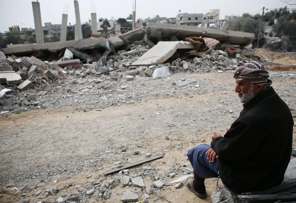 A Palestinian man sits near the damage to a building after an overnight Israeli air raid in Rafah, southern Gaza, March 29, 2024. (Photo: Ahmed Ibrahim/APA Images)