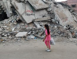 Girl walks past a destroyed building in Gaza City, with graffiti on the ruins saying, "We promise to rebuild," May 29, 2024. (Photo: Khaled Daoud/APA Images)