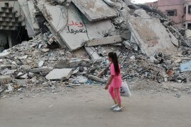 Girl walks past a destroyed building in Gaza City, with graffiti on the ruins saying, "We promise to rebuild," May 29, 2024. (Photo: Khaled Daoud/APA Images)