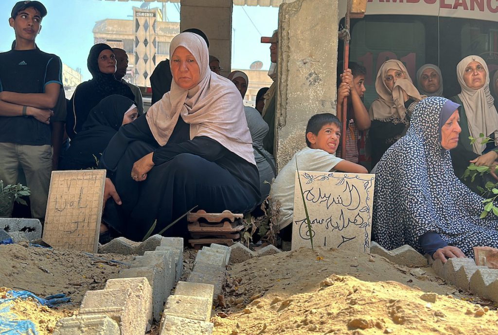 Palestinians gather as Civil Defense workers exhume 12 bodies from a mass grave inside the Al-Amal Hospital of the Red Crescent Society in Khan Younis, southern Gaza Strip, July 18, 2024. (Photo: Abdullah Abu Al-Khair/APA Images)