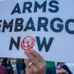 A protester holding up a sign calling for an arms embargo on Israel. (Photo: Social media)