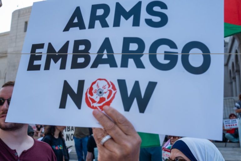 A protester holding up a sign calling for an arms embargo on Israel. (Photo: Social media)