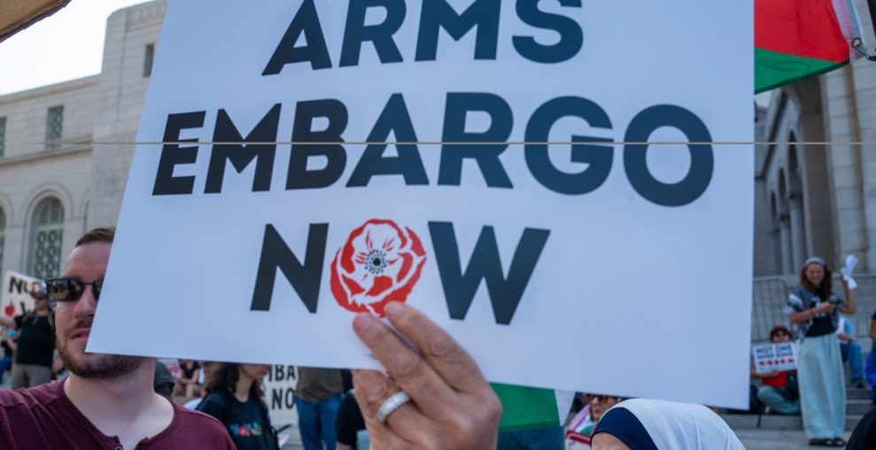 A protester holding up a sign calling for an arms embargo on Israel. (Photo: Social media)