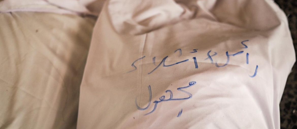A shroud covers the body of a man killed in the Fajr massacre at the Tabi'in School in Gaza City on August 10, 2024. The writing says "head + parts, unidentified martyr." (Photo: Fatima Hassona/Mondoweiss)