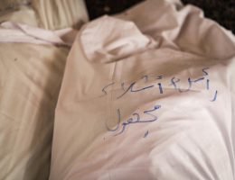 A shroud covers the body of a man killed in the Fajr massacre at the Tabi'in School in Gaza City on August 10, 2024. The writing says "head + parts, unidentified martyr." (Photo: Fatima Hassona/Mondoweiss)