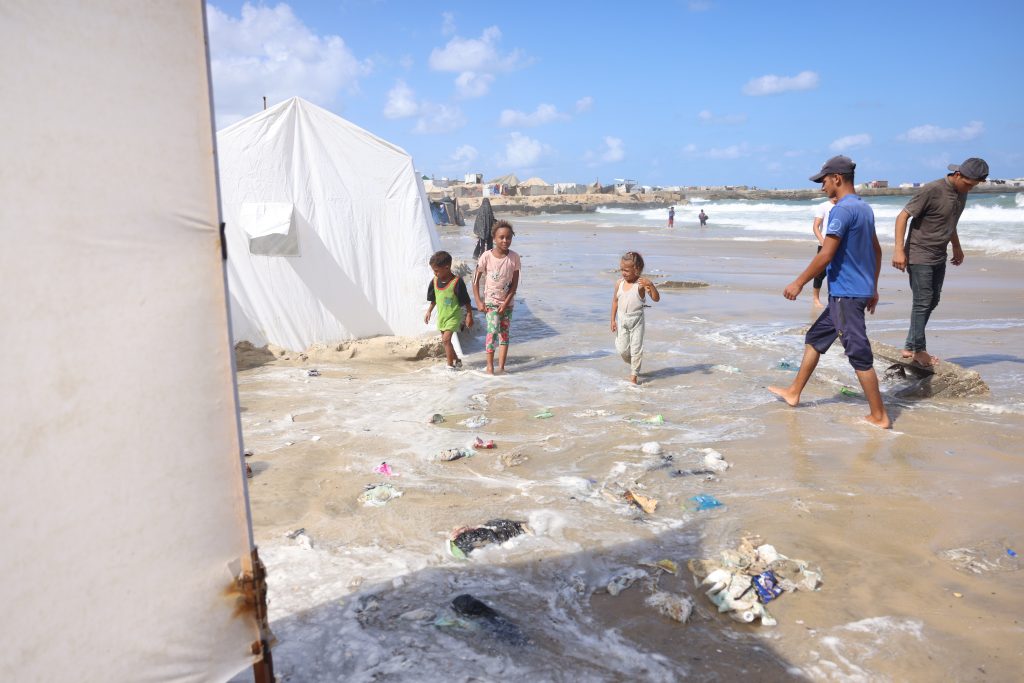 Displaced Palestinian families clear their tents of seawater after the tide damaged their encampment in Khan Younis, September 15, 2024. (Photo: Omar Ashtawy/APA Images)