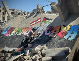 Displaced Palestinian artist Jamil al-Baz, 22, paints a mural on the rubble of destroyed homes in Khan Younis expressing solidarity with Lebanon, September 26, 2024. (Photo: Doaa Albaz/APA Images)