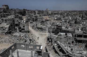 People walk past destroyed buildings in Khan Younis in the southern Gaza Strip on April 21, 2024 (Photo: Omar Ashtawy / APA Images)