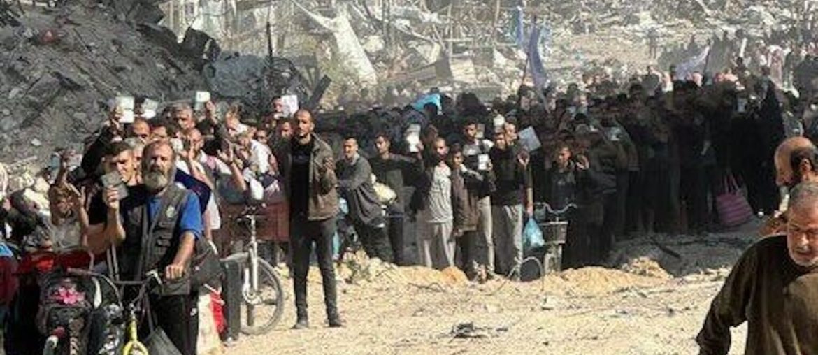 A crowd of Palestinians holding up their ID cards are forced to pass through an Israeli army checkpoint near Jabalia at gunpoint. (Photo: Social Media)