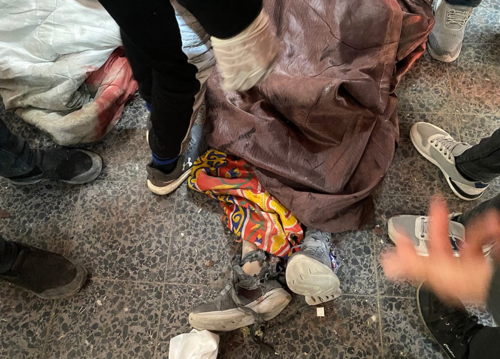 The body of a martyr killed in the Israeli airstrike on the Al-Hurriya School lays on the floor of the Arab Baptist Hospital, on November 26, 2024. (Photo: Hadi Daoud/APA Images)