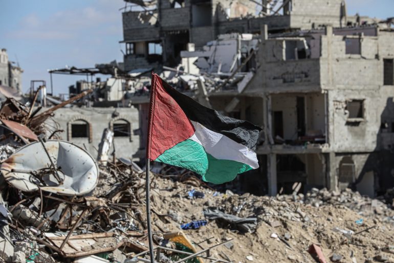 A Palestinian flag stands amid the rubble in the Gaza Strip on January 20, 2025. (Photo: Omar Ashtaw/ APA Images)