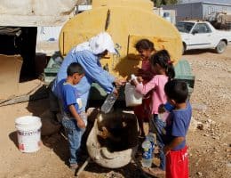 Palestinians fill plastic bottles and jerry cans with drinking water from a water tank in the West Bank village of Um al-Khair south of Hebron, August 17, 2016. (Photo: Wisam Hashlamoun/APA Images)