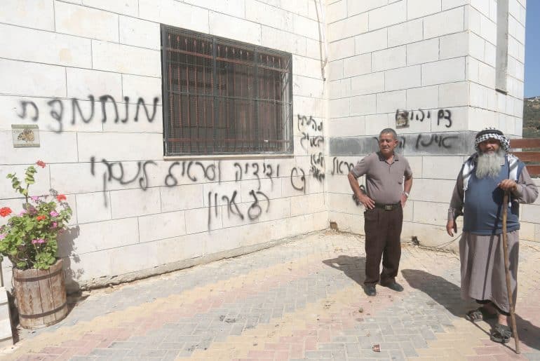 Palestinians inspect a burned-out mosque in the village of Aqraba, south of Nablus in the West Bank, after Israeli settlers set fire to the entrance and spray-painted Hebrew graffiti on the walls. (Photo: Mohammed Nasser/APA Images)