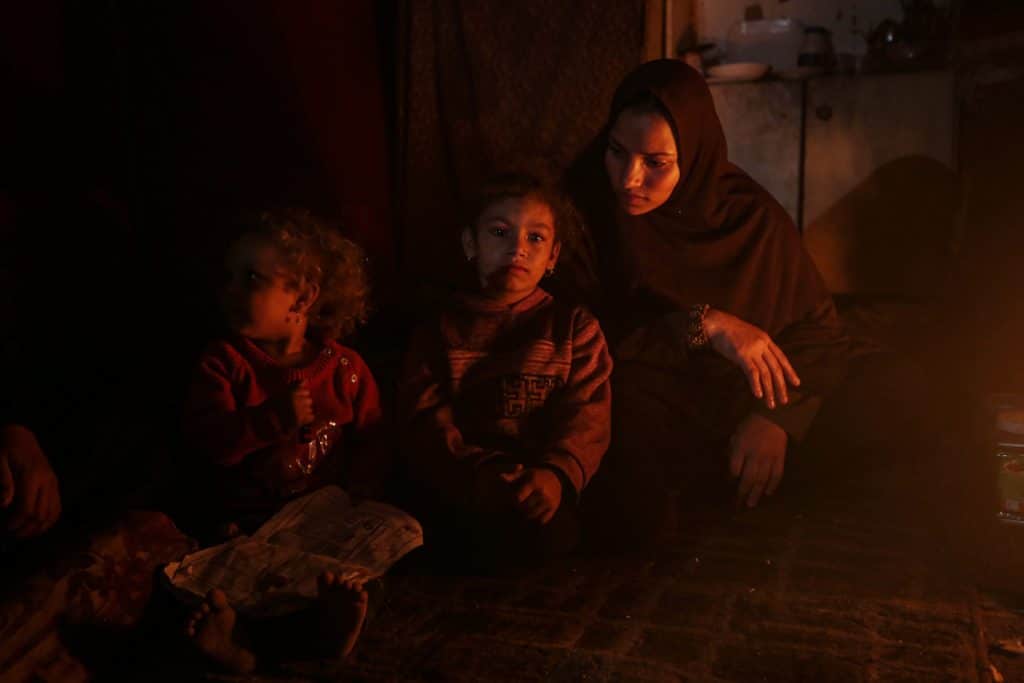 Palestinian families set fire to makeshift tents in Gaza to cope with power shortages, while devastated streets and debris surround their shelters in Gaza City on November 5, 2025. (Photo: Omar Ashtawy/APA Images)