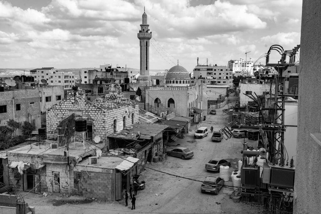 A view of Jenin refugee camp in October 2024. The refugee camp is known as a symbol of resistance in the West Bank and home to several armed groups. With several militias operating in the camp, Jenin was often subjected to heavy raids by the Israeli army, with drone and airstrikes occurring frequently. Posters of resistance fighters killed in Jenin can be seen on a wall in Jenin refugee camp. Many walls are covered in bullet holes from raids. Israeli soldiers also deface posters of fighters when they occupy the camp. (Photo: David Lombeida)