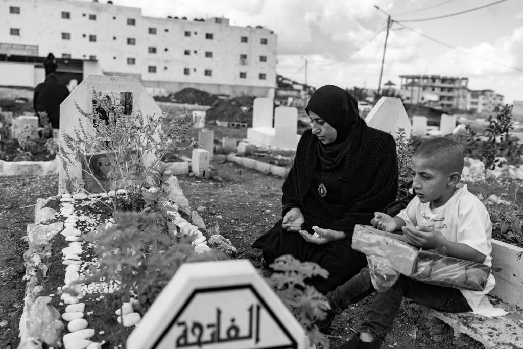 A Jenin resident mourns the loss of her son, who was killed in November 2023 in Jenin refugee camp during an Israeli army raid. There is a martyrs' cemetery in Jenin, but it has recently become completely filled due to intensified clashes with the Israeli army. A new cemetery is being built on open ground near the camp, where a mother and son mourn their loved one. (Photo: David Lombeida)