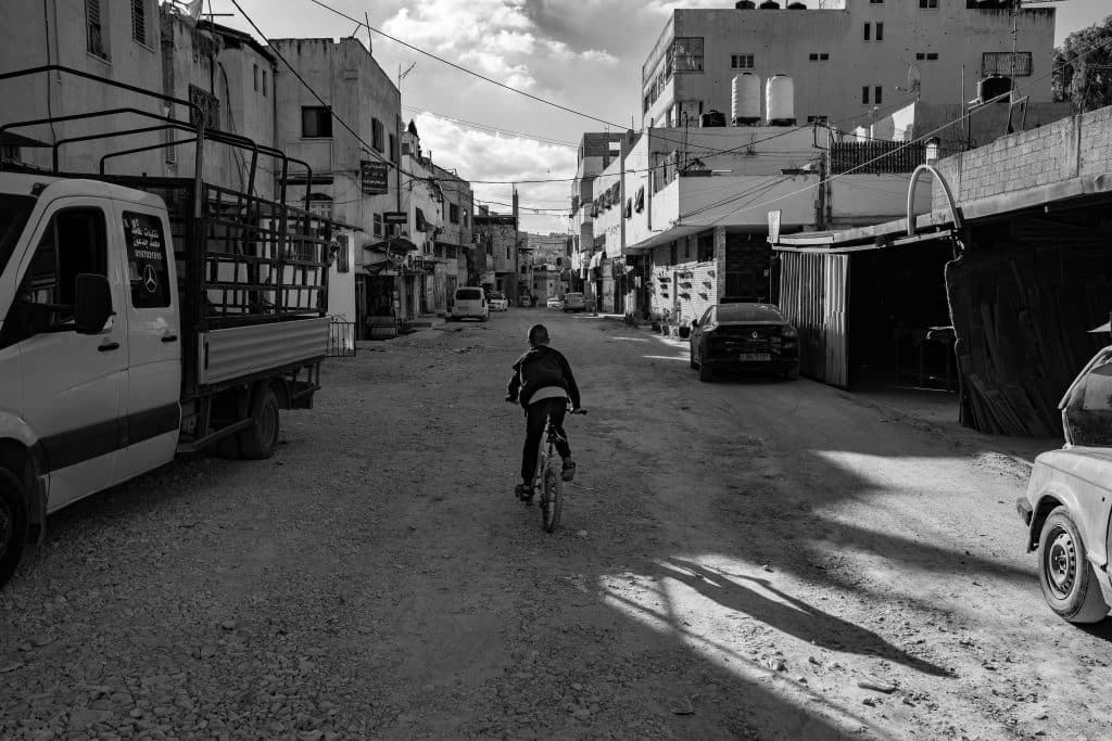 A child rides his bicycle through Jenin refugee camp. (Photo: David Lombeida)