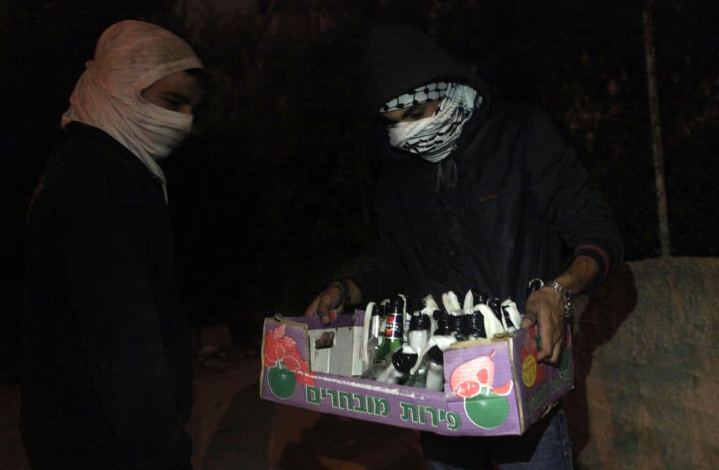 Jóvenes palestinos preparan cócteles molotov antes de enfrentarse a soldados israelíes en protesta contra la guerra israelí en Gaza, julio de 2014, cerca del asentamiento israelí de Beit El. (Foto: Shadi Hatem/APA Images)