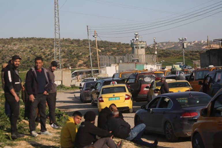 Palestinians wait at an Israeli military checkpoint near Nablus after Israeli forces close checkpoints and iron gates at the entrances of Palestinian cities during the ongoing U.S.-Israeli war on Iran, March 3, 2026. (Photo: Mohammed Nasser/APA Images)